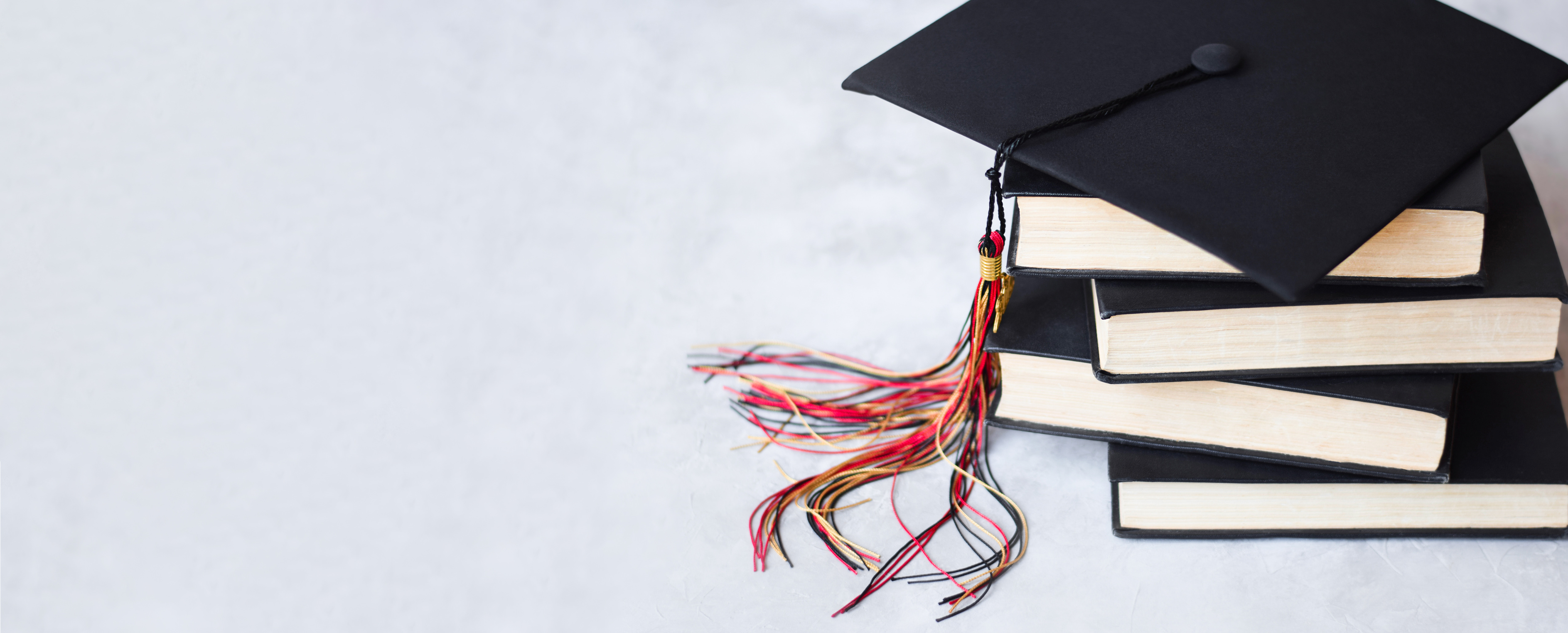 Graduation Cap on Stack of Books on Grey Background Web Banner
